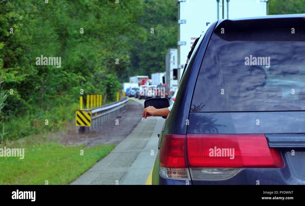 A cigarette in this driver`s hand sticking out of his car during the typical rush hour madness. Stock Photo